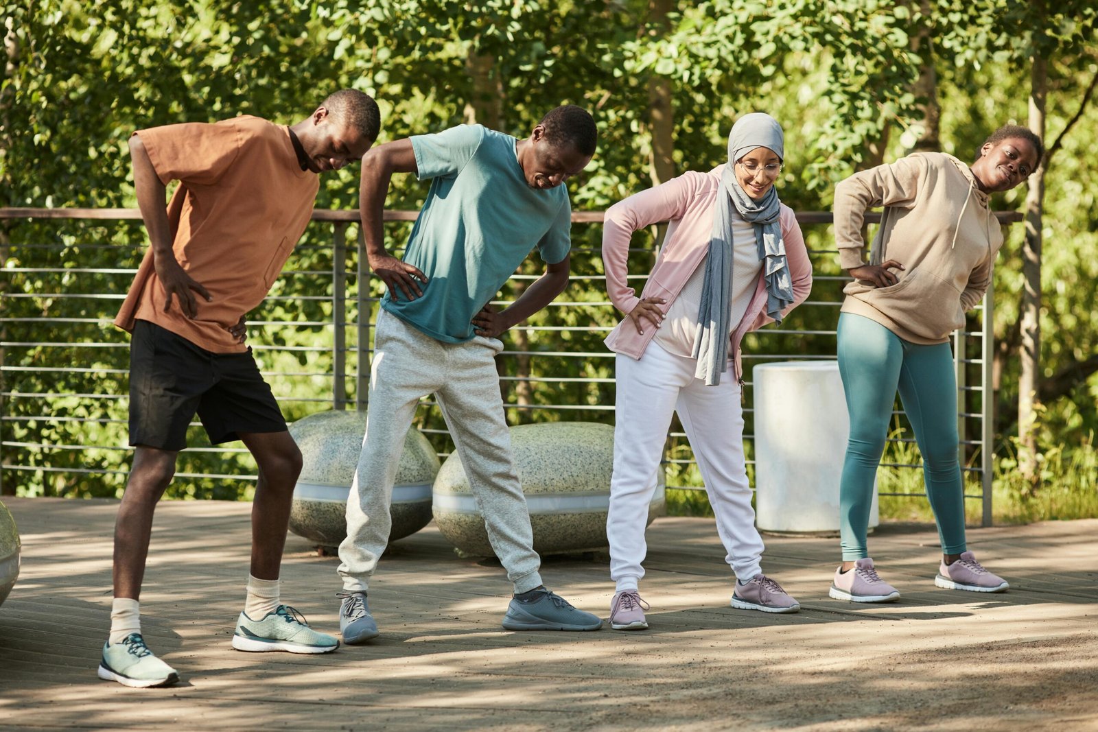 Diverse group of adults exercising together outdoors in a park on a sunny day.